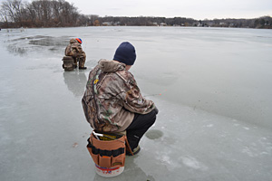 Two ice anglers search for the ice fishing bite on a lake