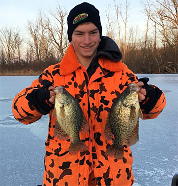 A young angler with two big crappie caught through the ice